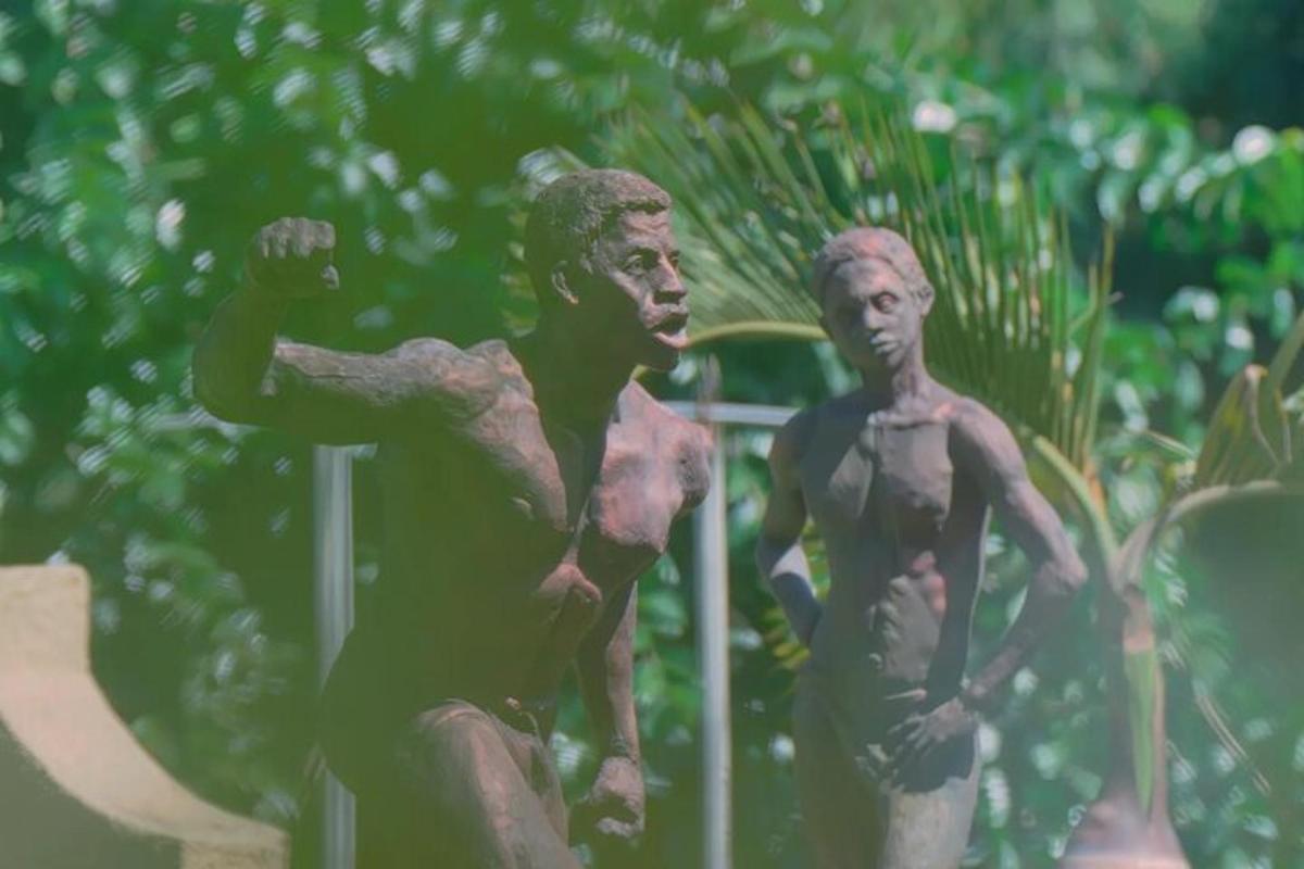 Dos estatuas de dos hombres sentados en una valla