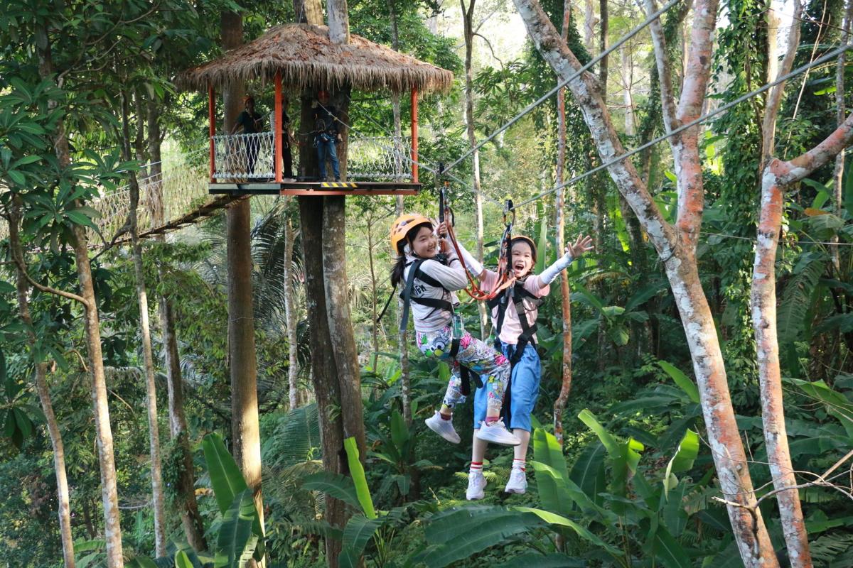 hai cô gái đang đu mình trên đường trượt zipline trong rừng