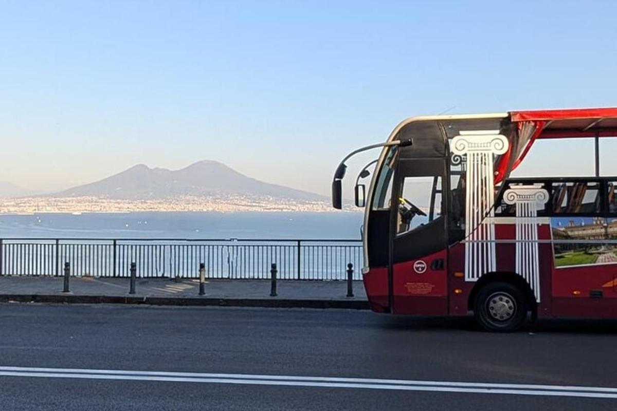 en rød buss som kjører nedover en vei ved siden av havet
