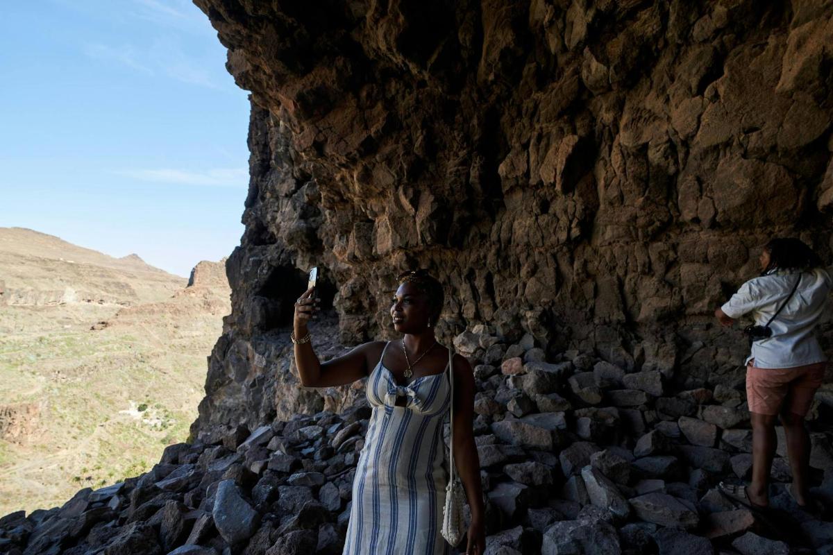 una donna in abito in piedi accanto a una parete rocciosa
