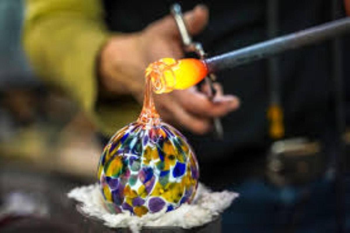 osoba řezající skleněnou ozdobu nůžkami