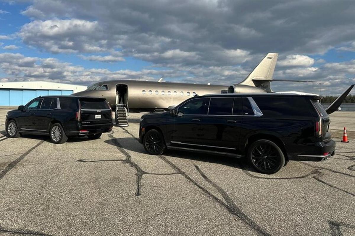 Dos vehículos están estacionados al lado de un avión.