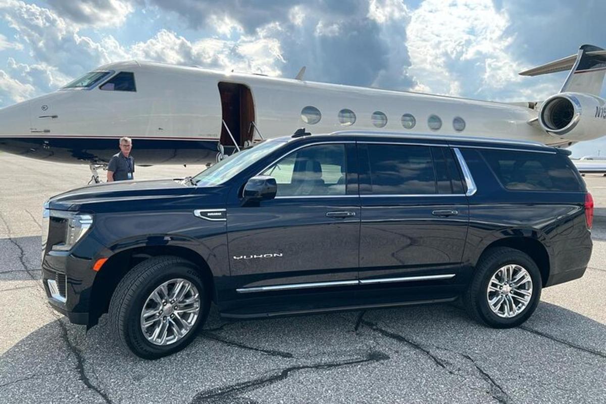 Una camioneta negra estacionada frente a un avión