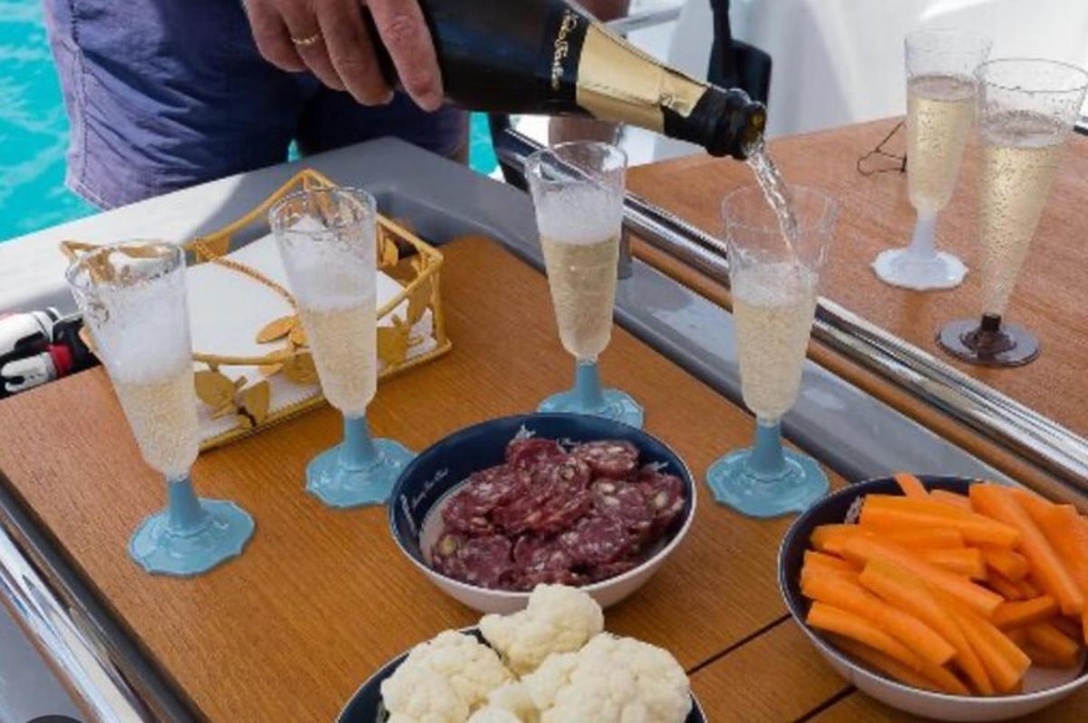 seseorang menuang champagne ke dalam gelas di atas meja dengan makanan
