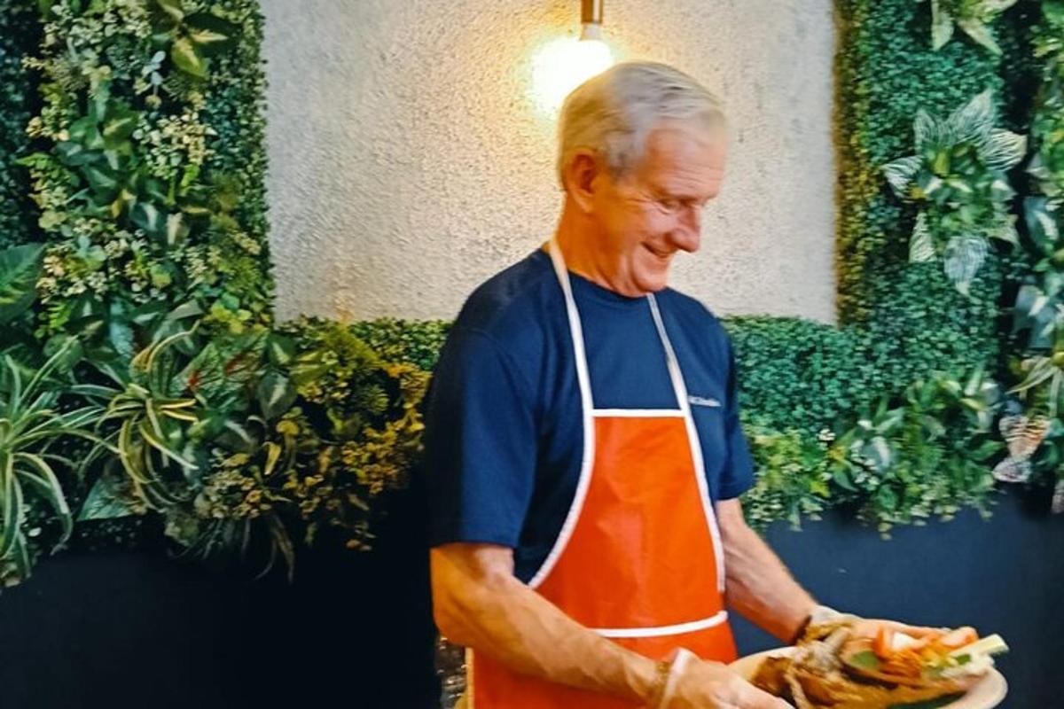 moški v predpasniku, ki drži krožnik hrane