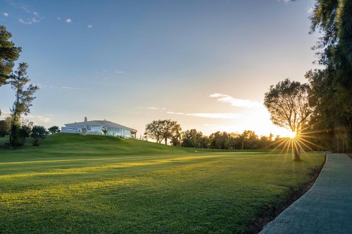 a house on a golf course with the sun setting