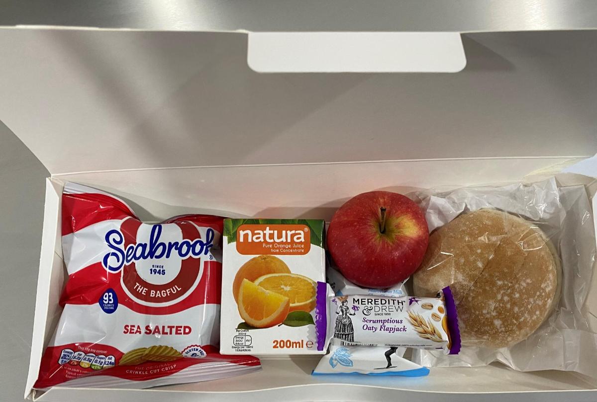 Un refrigerador abierto con un sándwich, una manzana y comida.