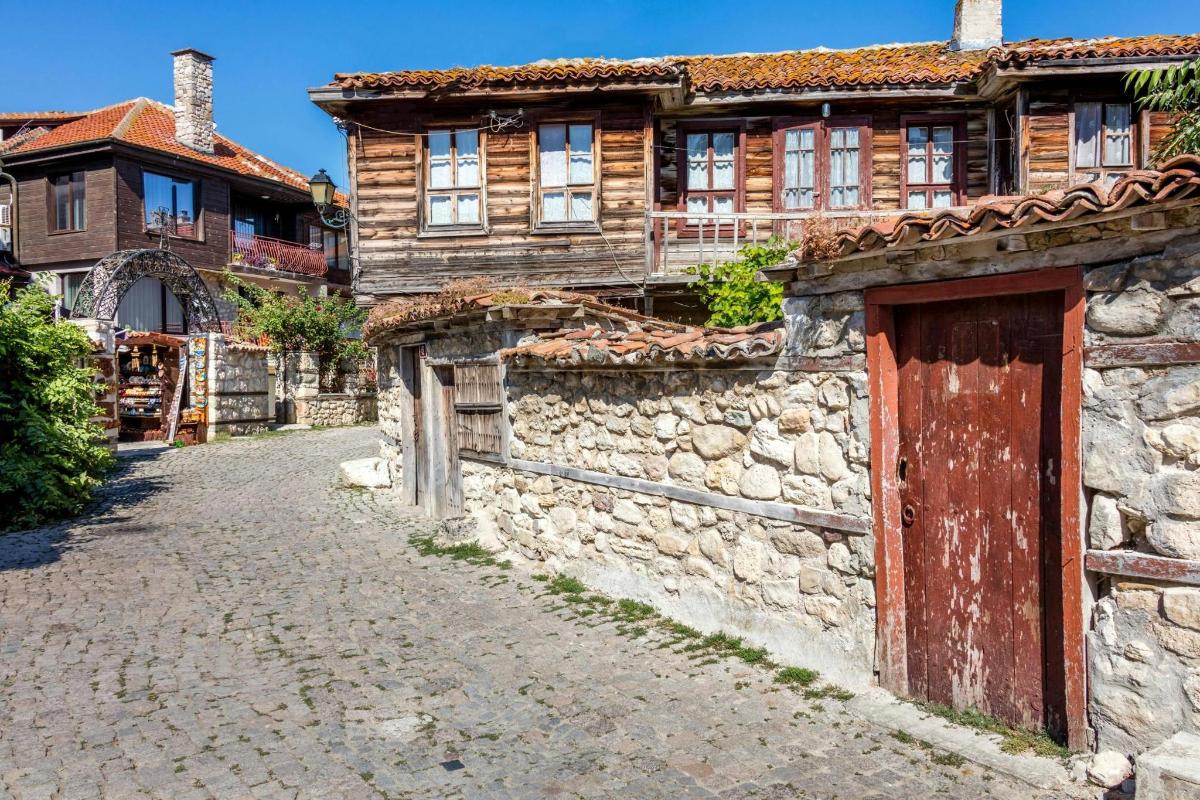 an old stone building with a red door on a street