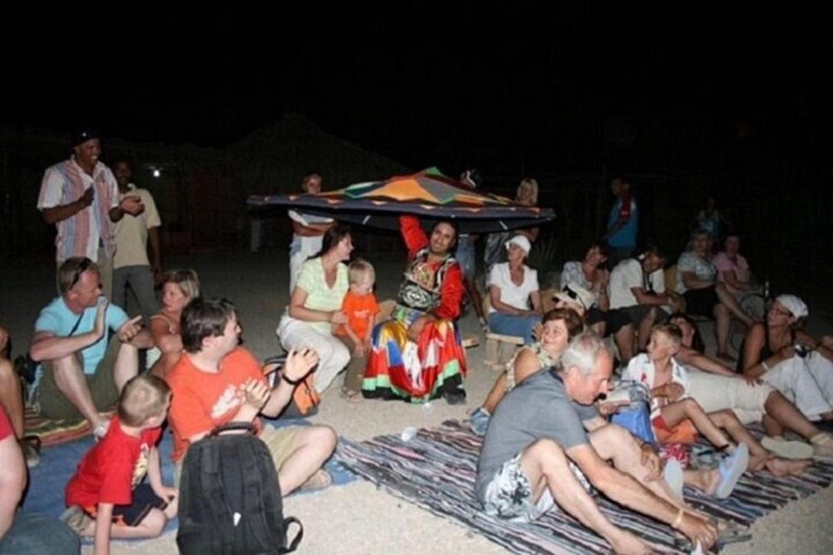een groep mensen die 's avonds op het strand zit