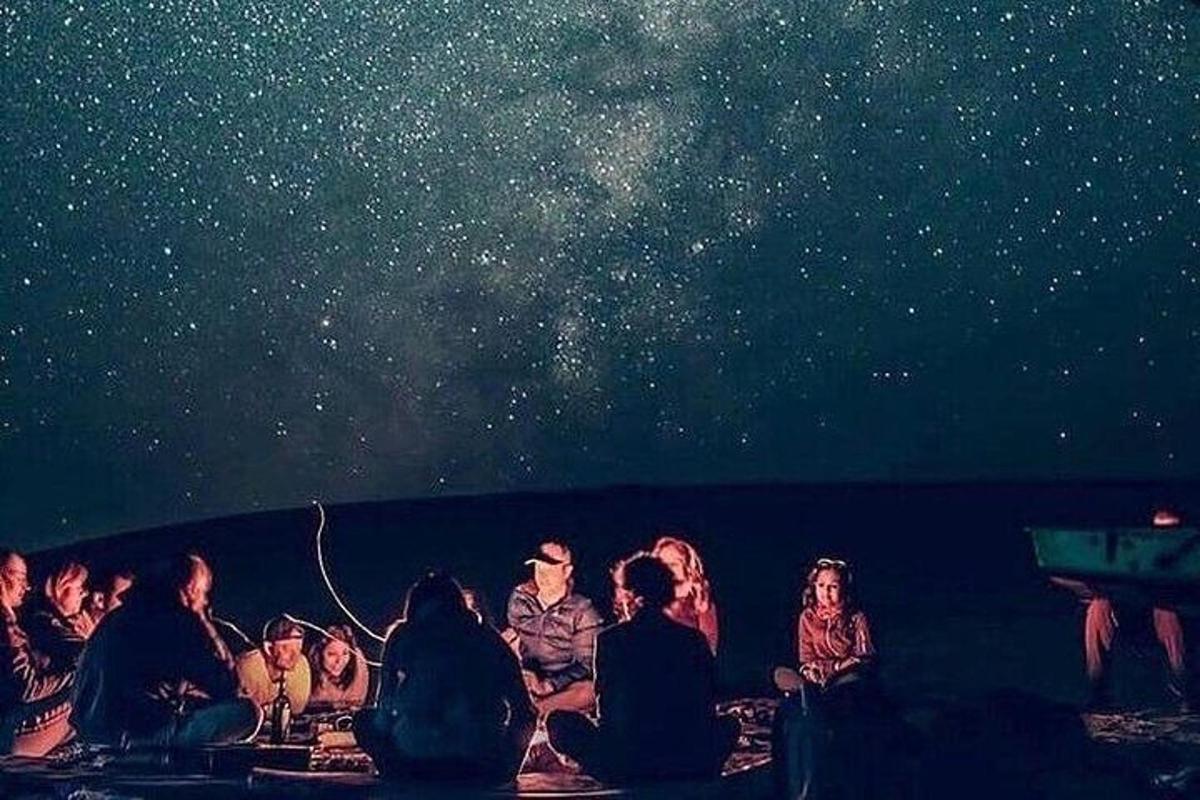 un gruppo di persone sedute sulla spiaggia che guardano l'universo
