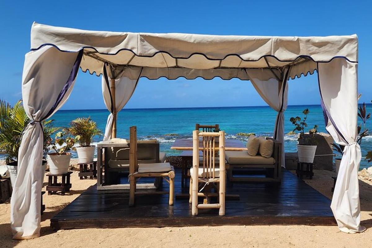 a gazebo on the beach with chairs and the ocean