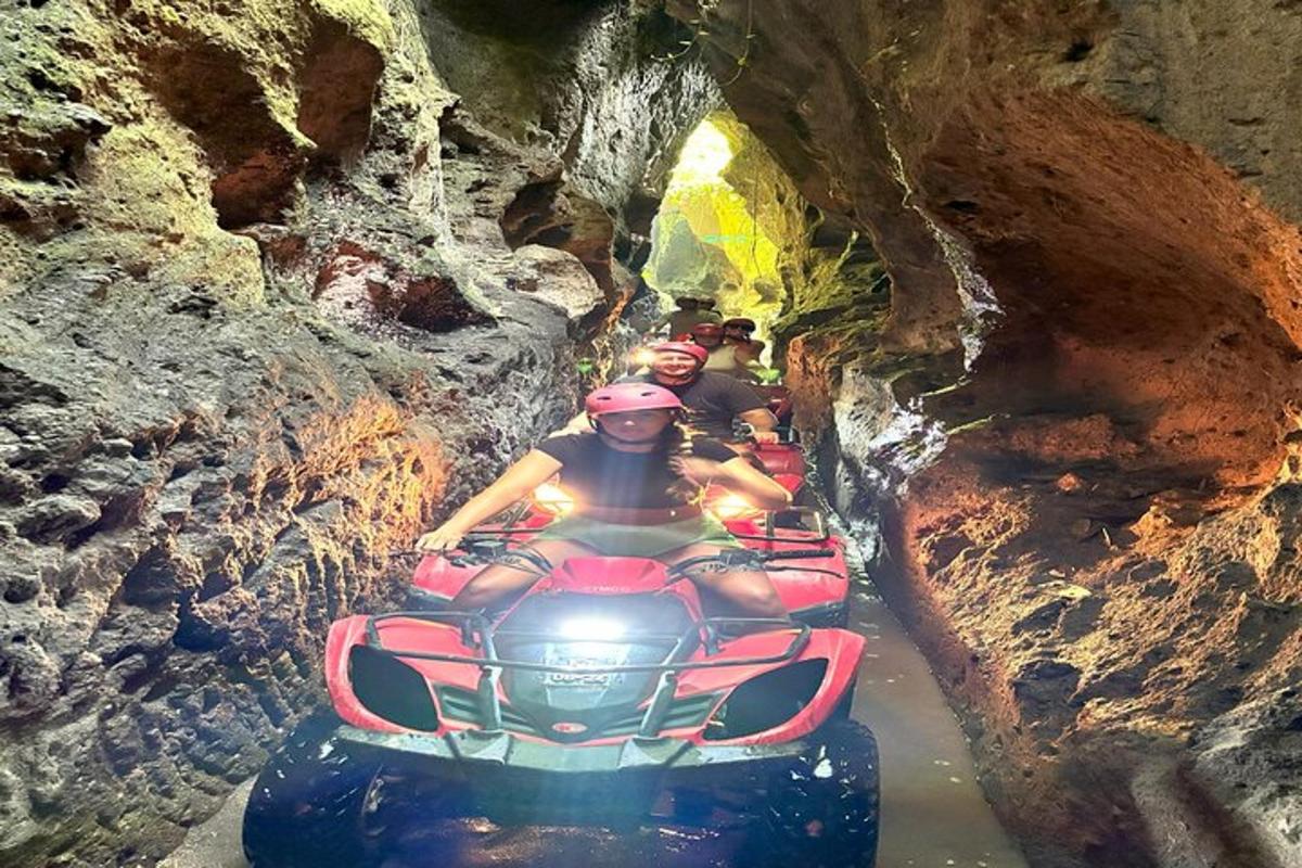 skupina lidí jedoucích na čtyřkolce jeskyní