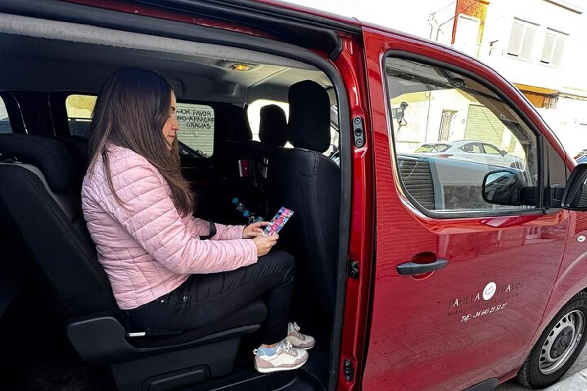 žena sedící v zadní části dodávky a dívající se do svého mobilního telefonu