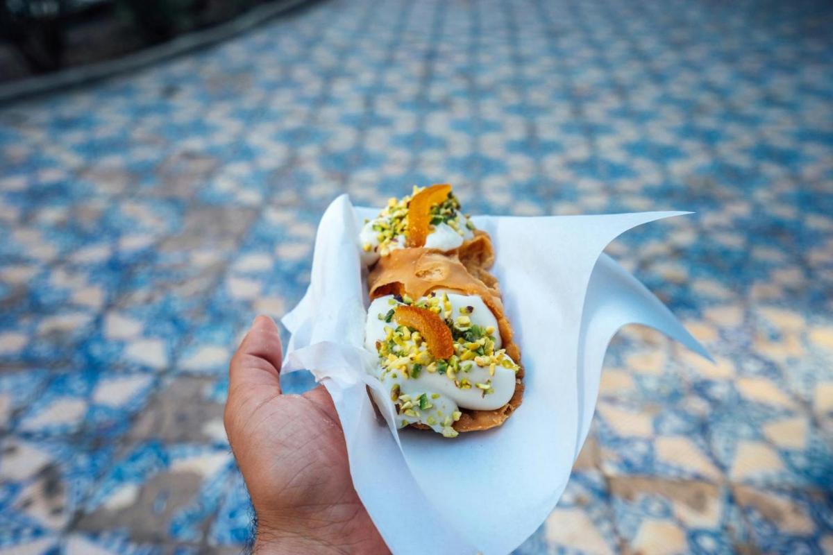 a person holding a hot dog in a paper wrapper