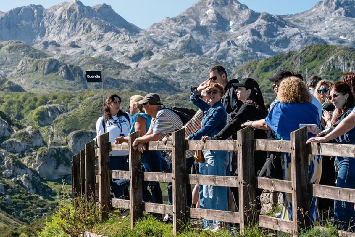 a crowd of people looking over a fence with mountains in the background