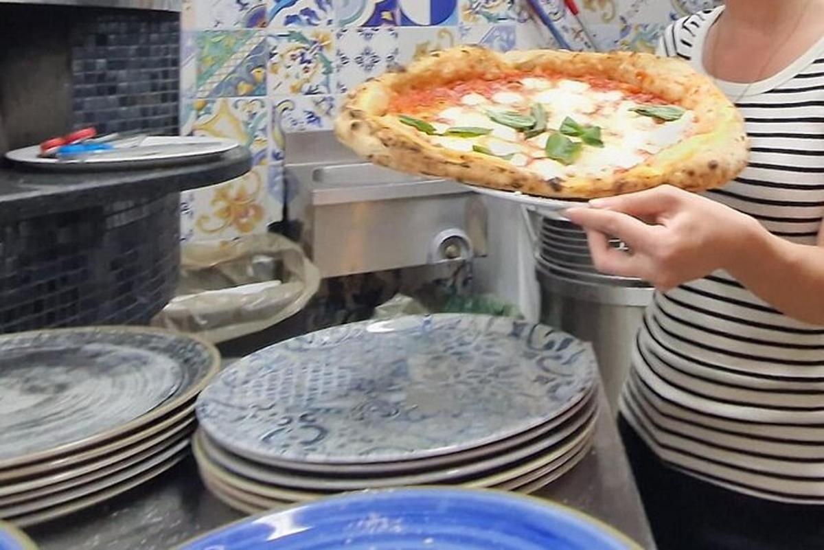 una dona que sosté una pizza en una safata amb plats