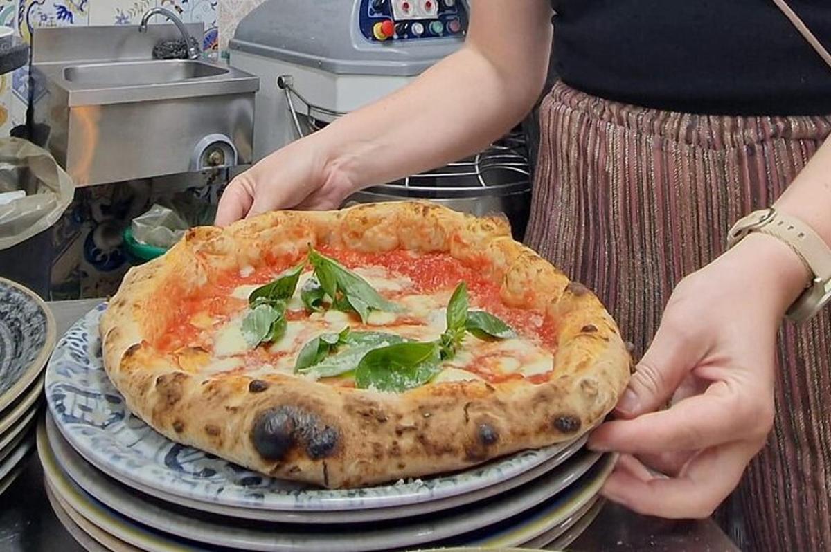 una dona que sosté una pizza sobre una pila de plats