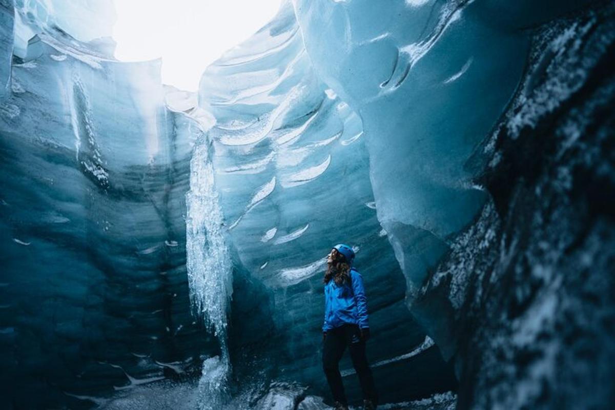 uma pessoa em pé em frente a uma caverna de gelo