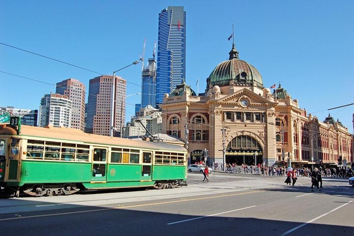 a green tram on a city street in front of a building
