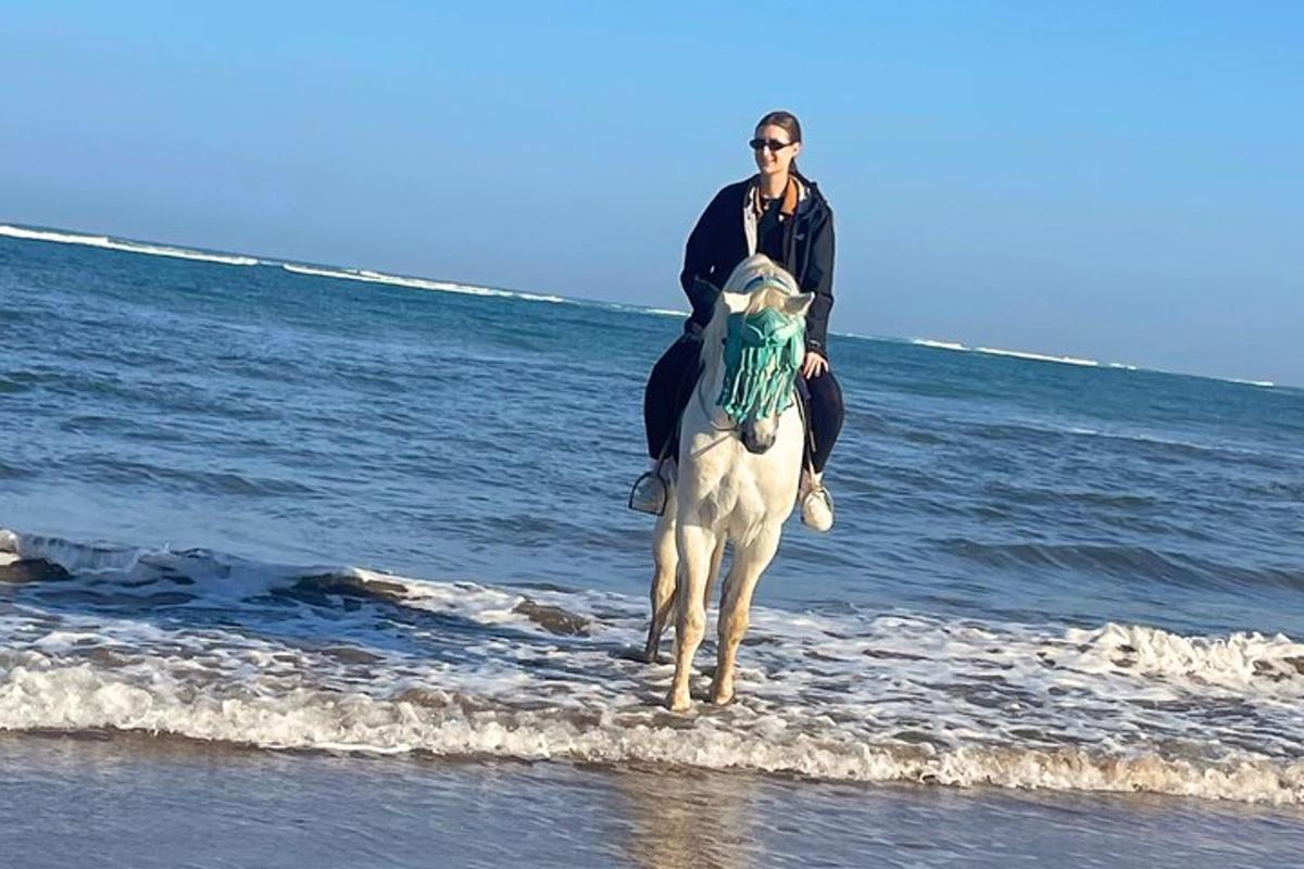 a man riding a white horse on the beach