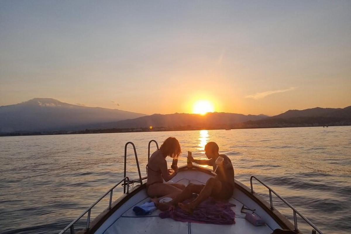duas pessoas sentadas em um barco na água ao pôr do sol