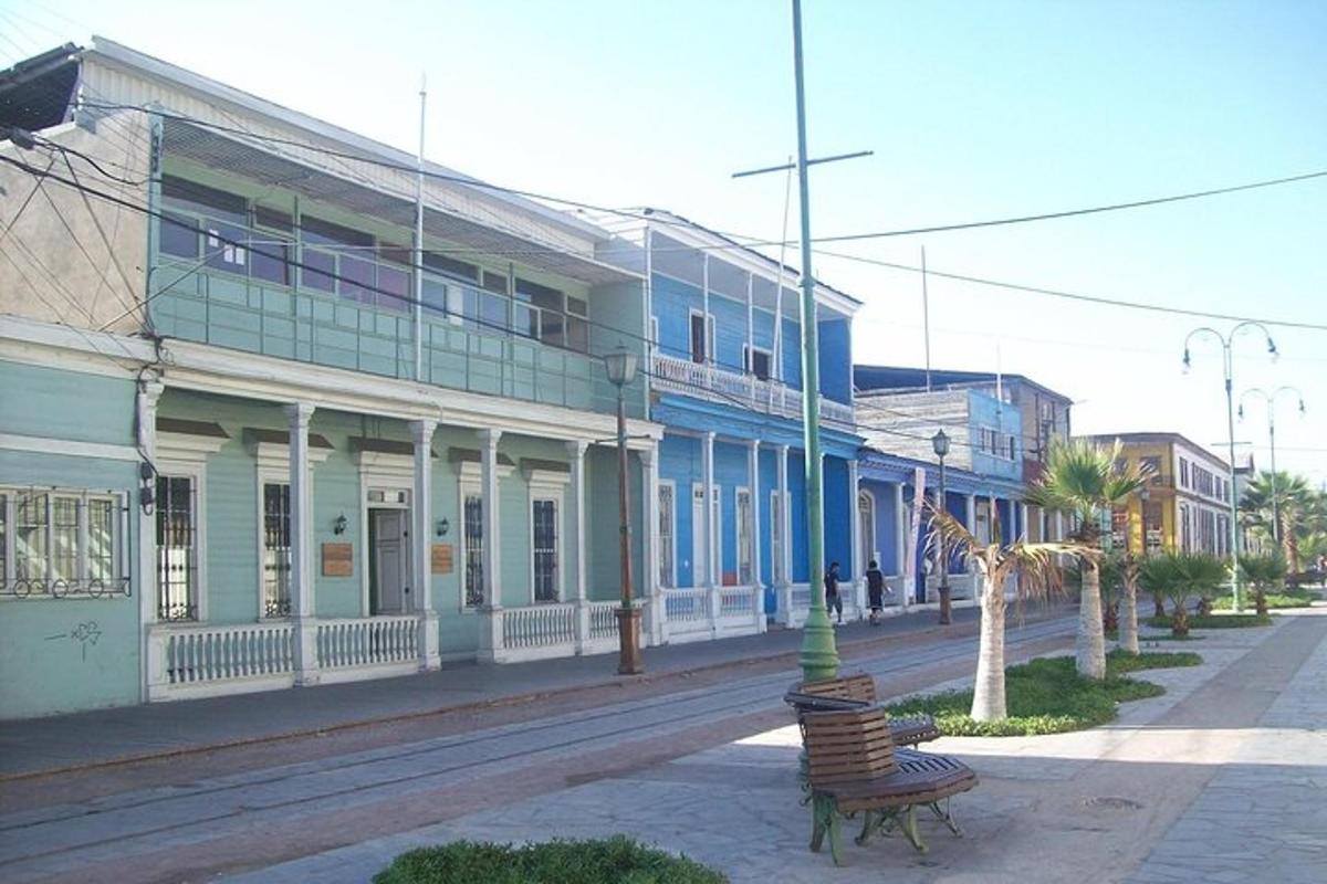 a city street with blue and white buildings and a bench