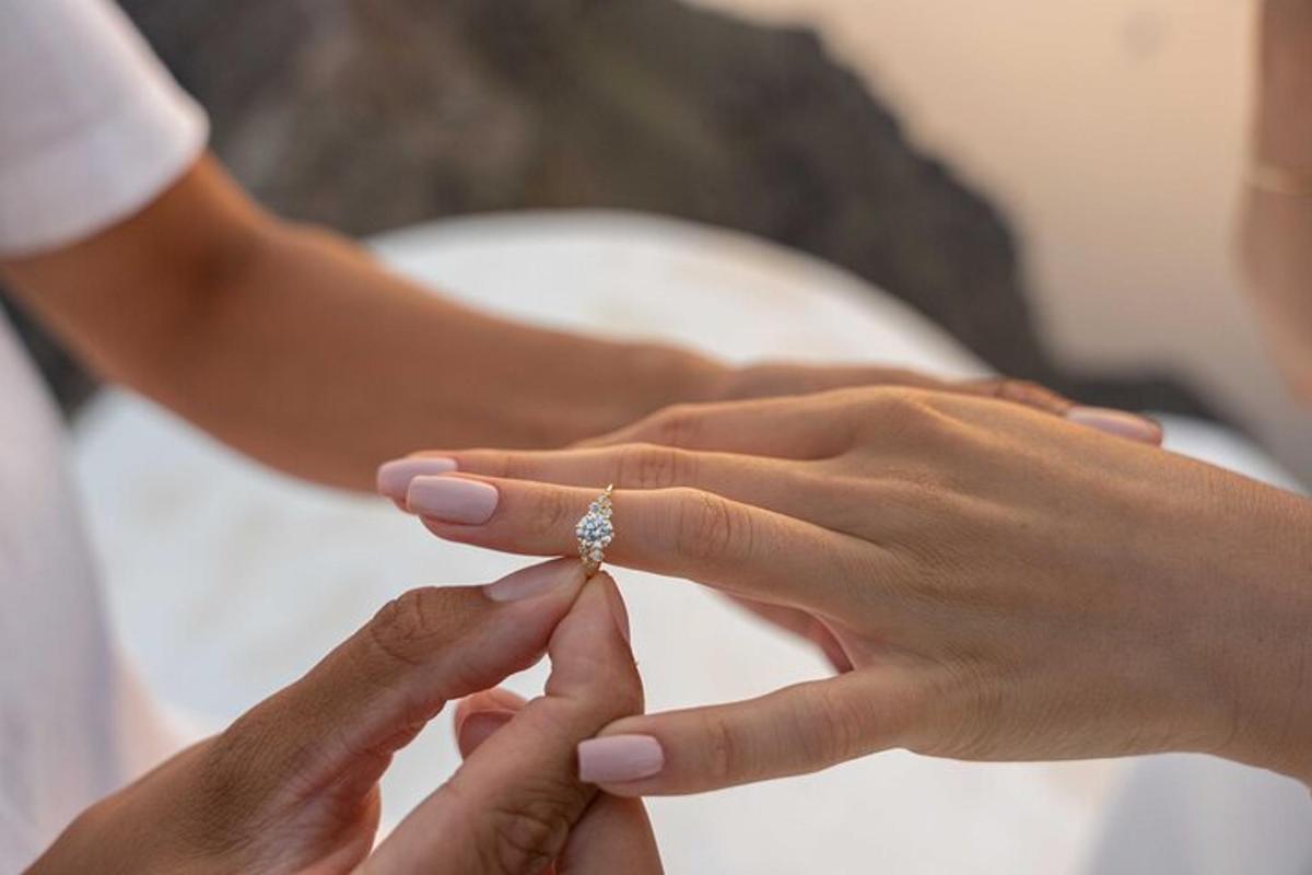 en brud og brudgom holder hænder med deres forlovelsesring