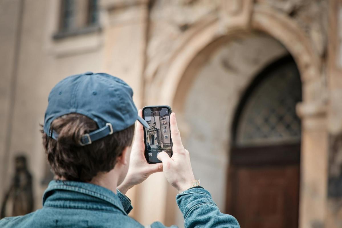 moški, ki fotografira stavbo z mobilnim telefonom