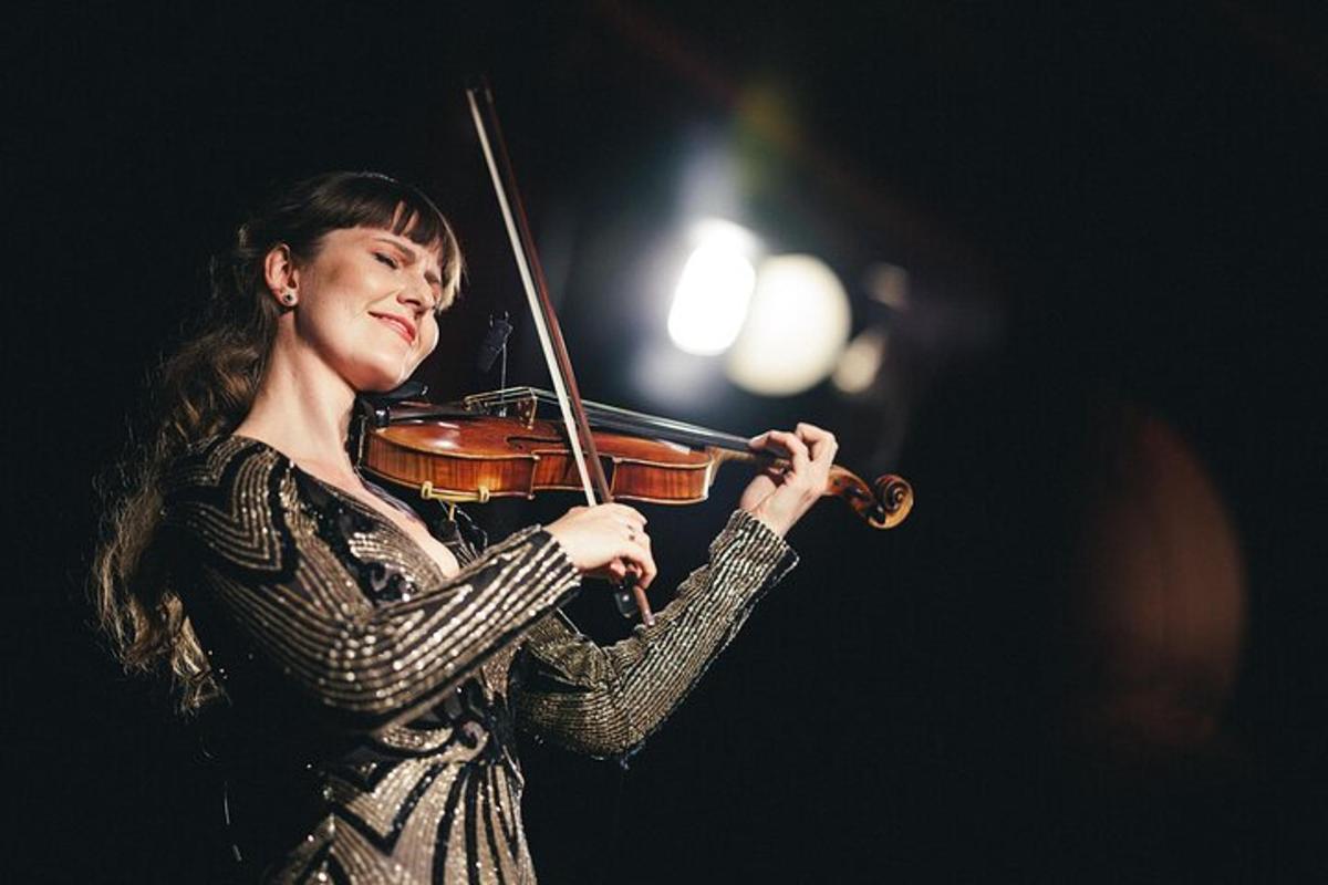 una donna che suona il violino in una stanza buia