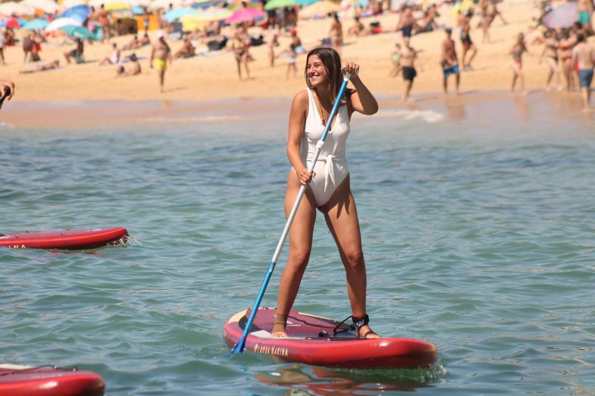o femeie stă pe o placă de paddle pe plajă
