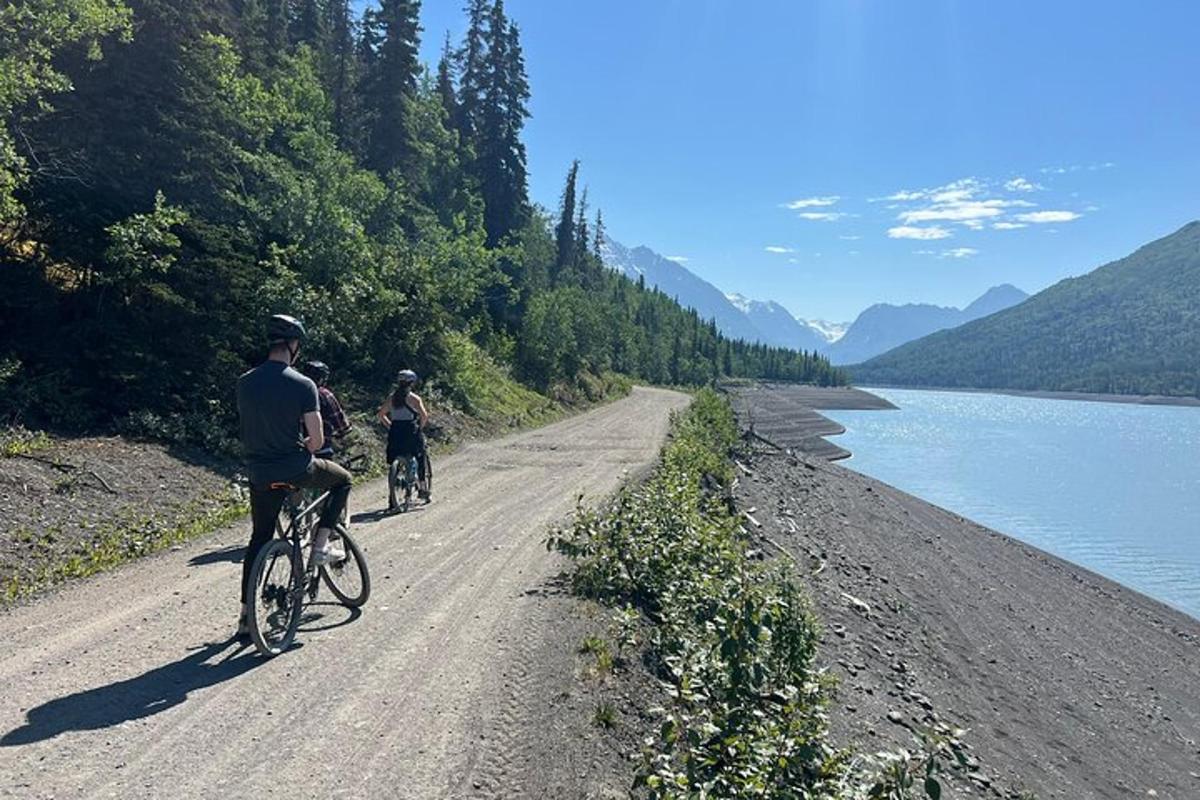 dues persones anant en bicicleta per un camí de terra al costat d'un riu