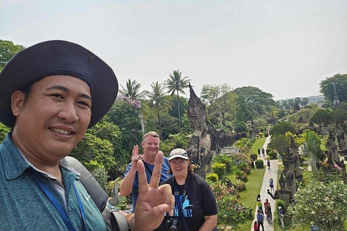 a man giving the peace sign while standing in front of a garden