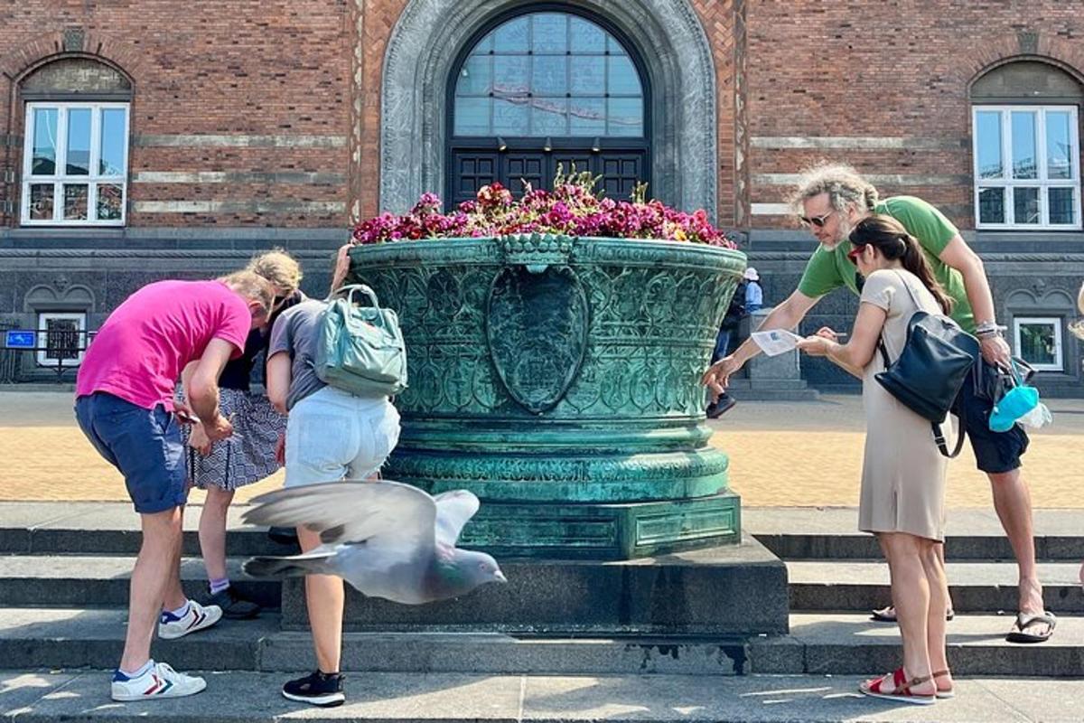 hópur fólks stendur í kringum vasa með fugli