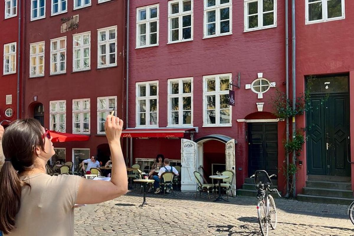 Una mujer tomando una fotografía de un edificio rojo.