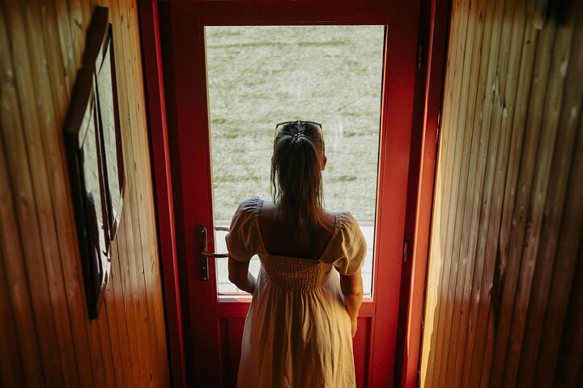 a woman in a yellow dress looking out of a door