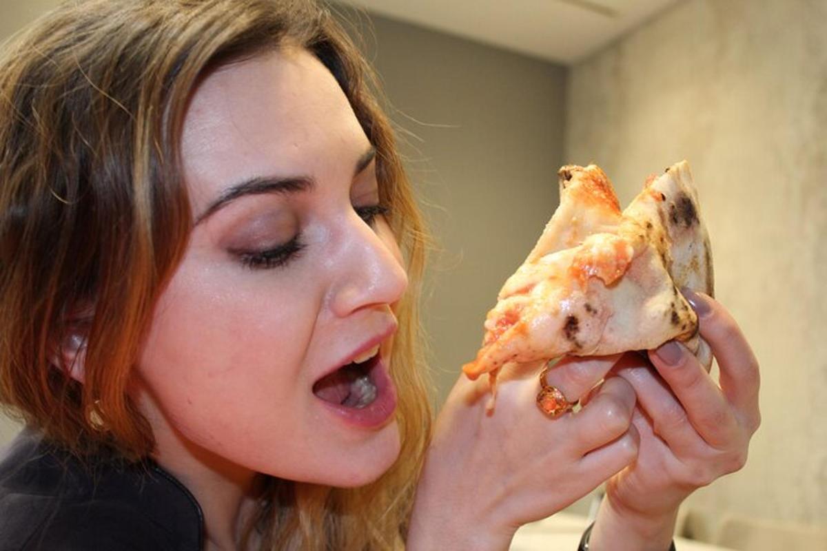o femeie mănâncă o felie de pizza