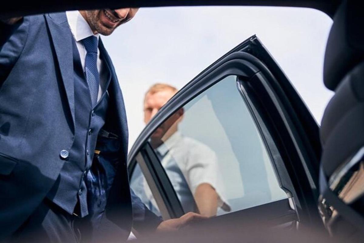 a man in a suit standing next to a car