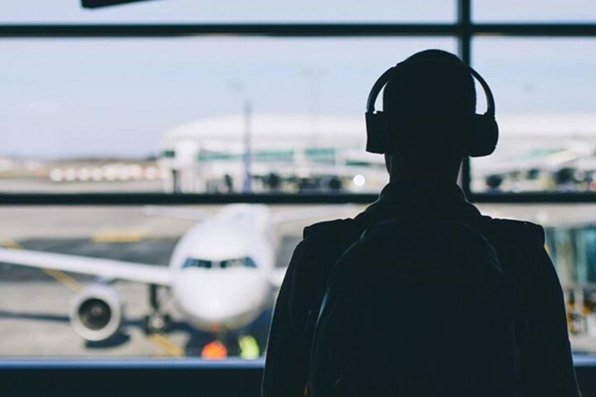 a person wearing headphones looking at an airplane at an airport