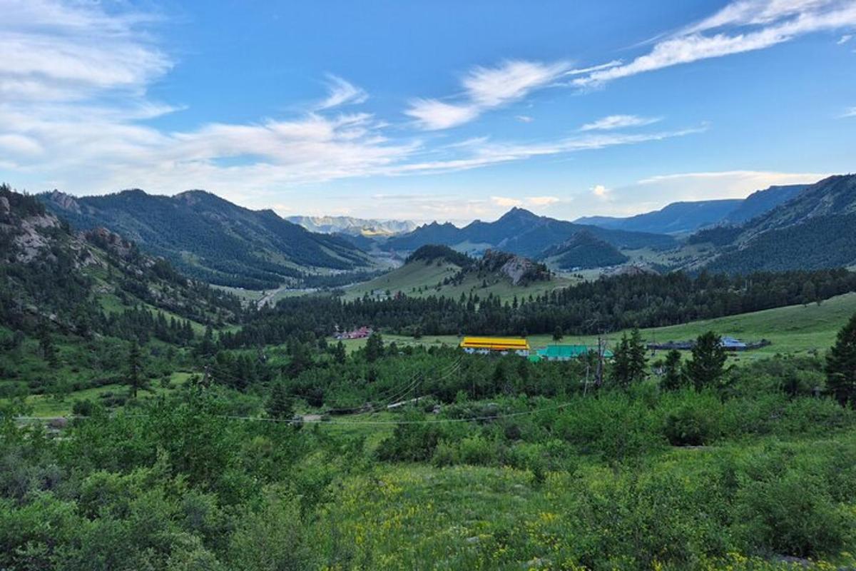 a view of a valley with mountains and a yellow building