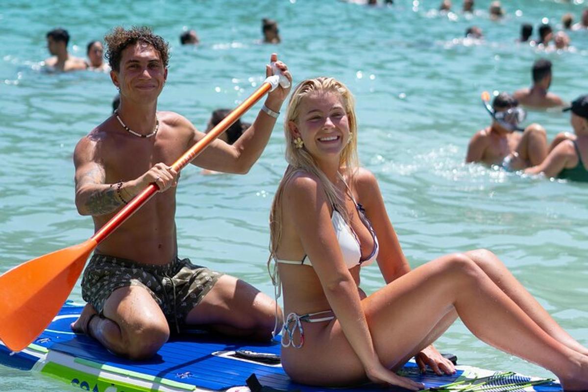 un uomo e una donna seduti su una tavola da paddle in acqua