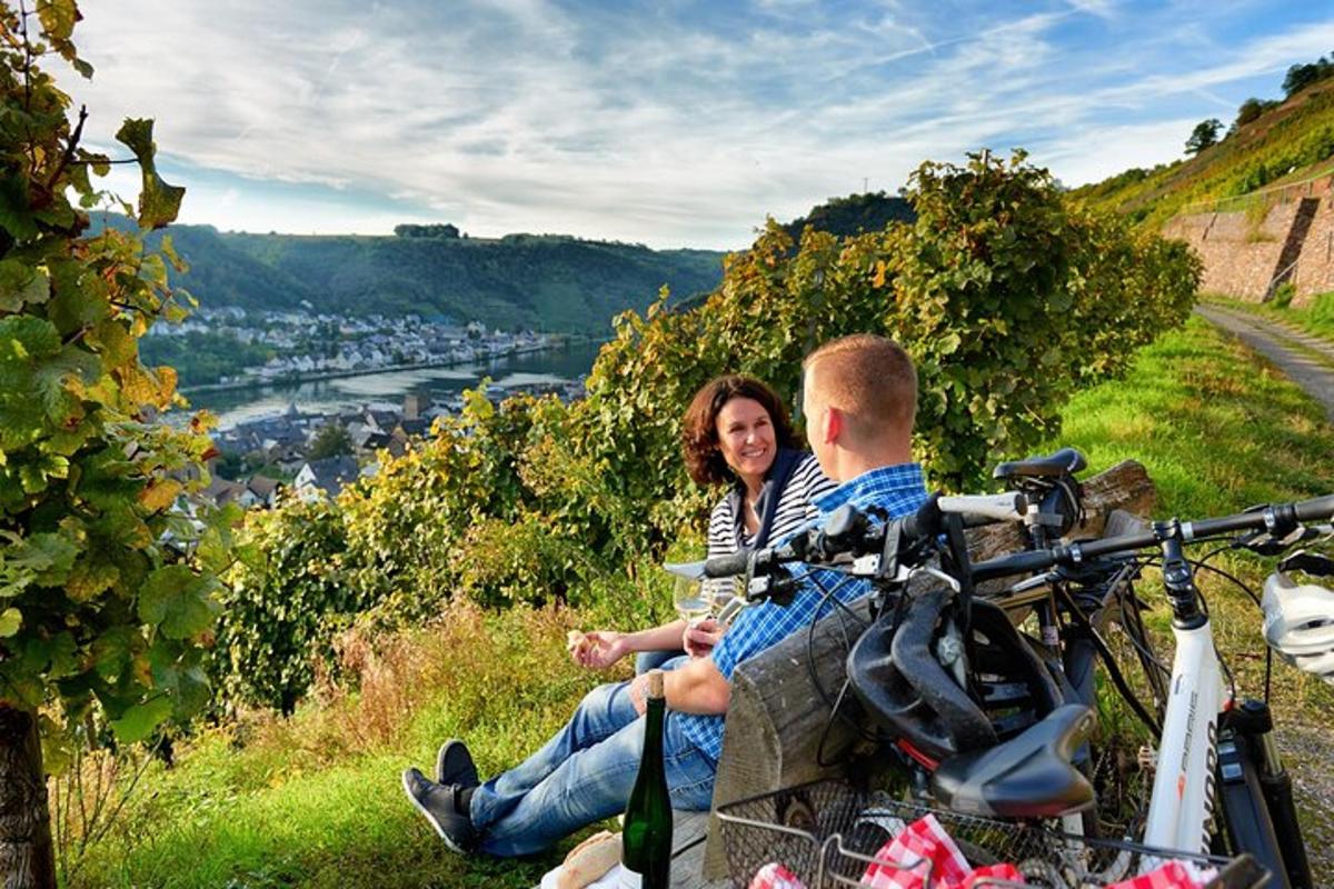a man and a woman sitting on a hill with a bike