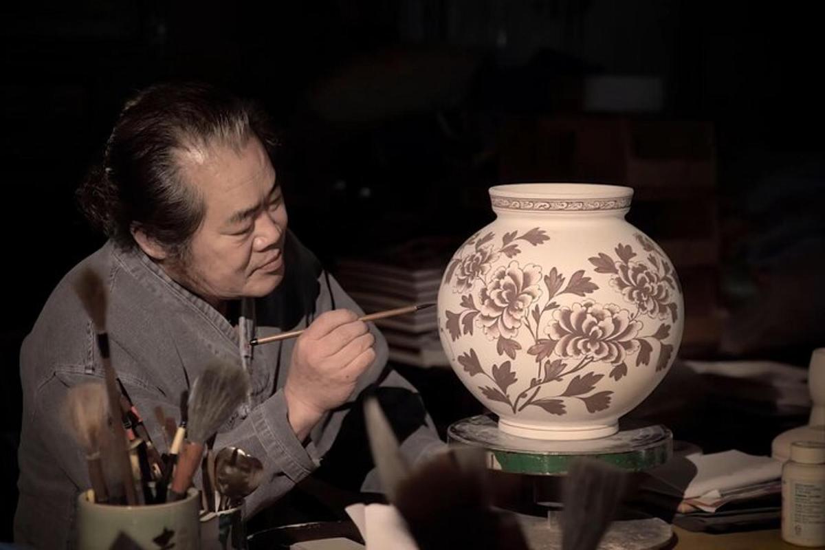a woman painting a vase on a table