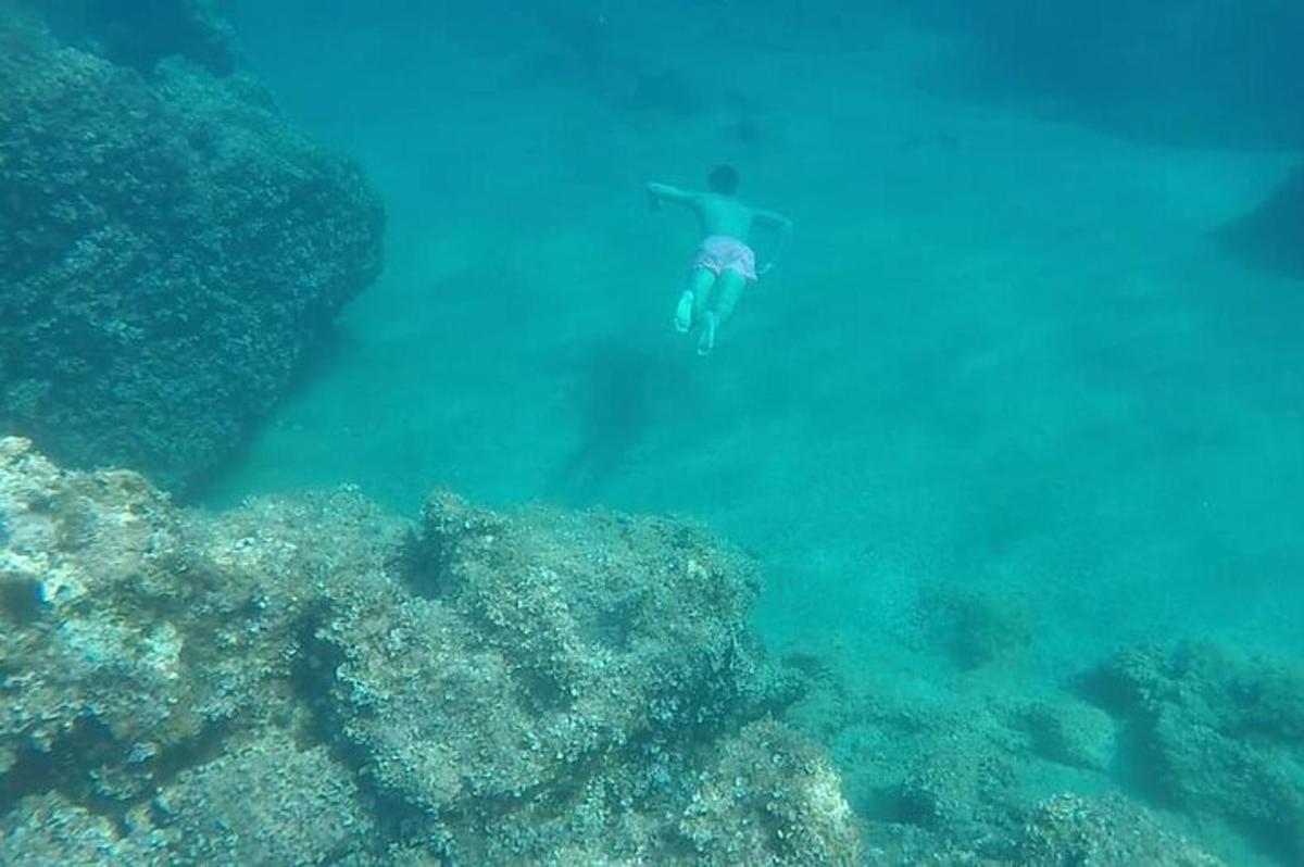 a person swimming in the ocean next to a reef