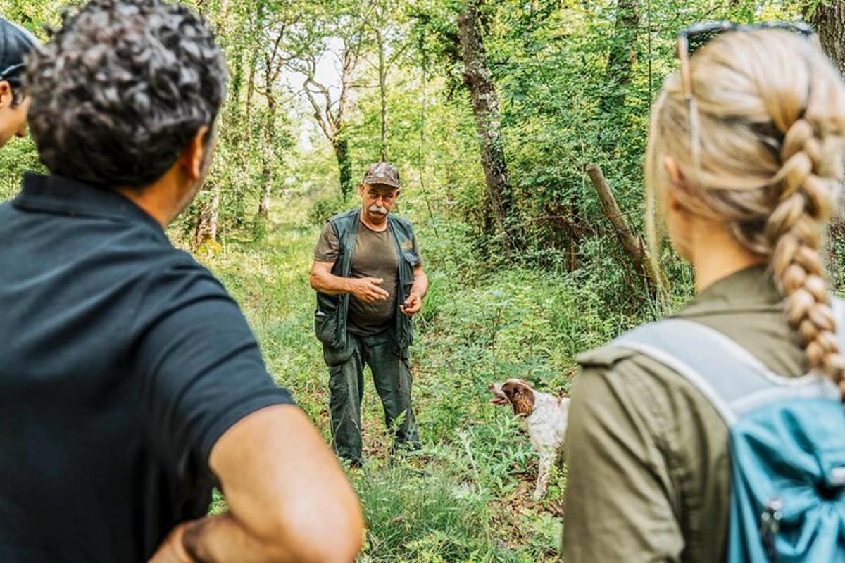 cilvēku grupa, kas stāv mežā kopā ar vīrieti