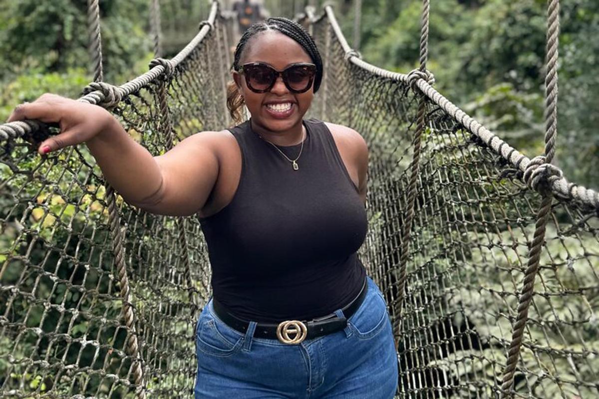 a woman in a black shirt standing on a suspension bridge