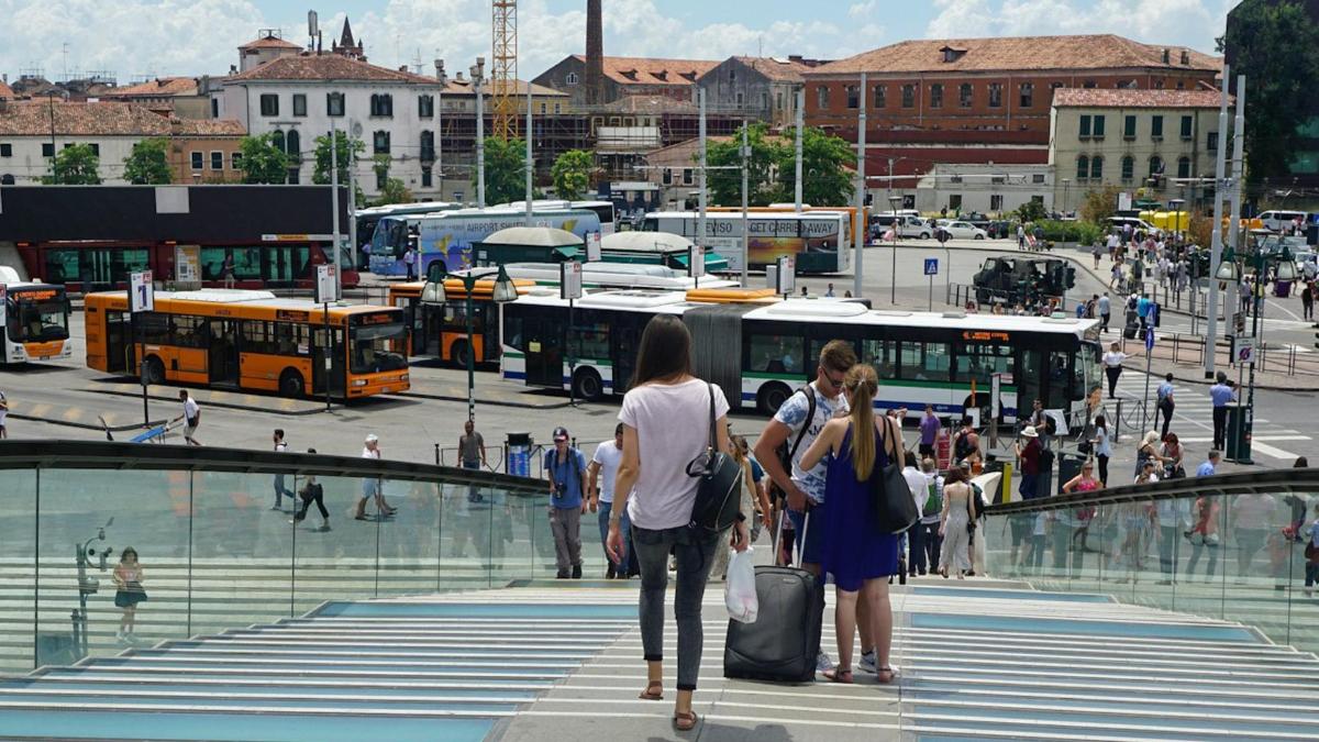 grupp inimesi, kes kõnnivad üle tänava bussidega