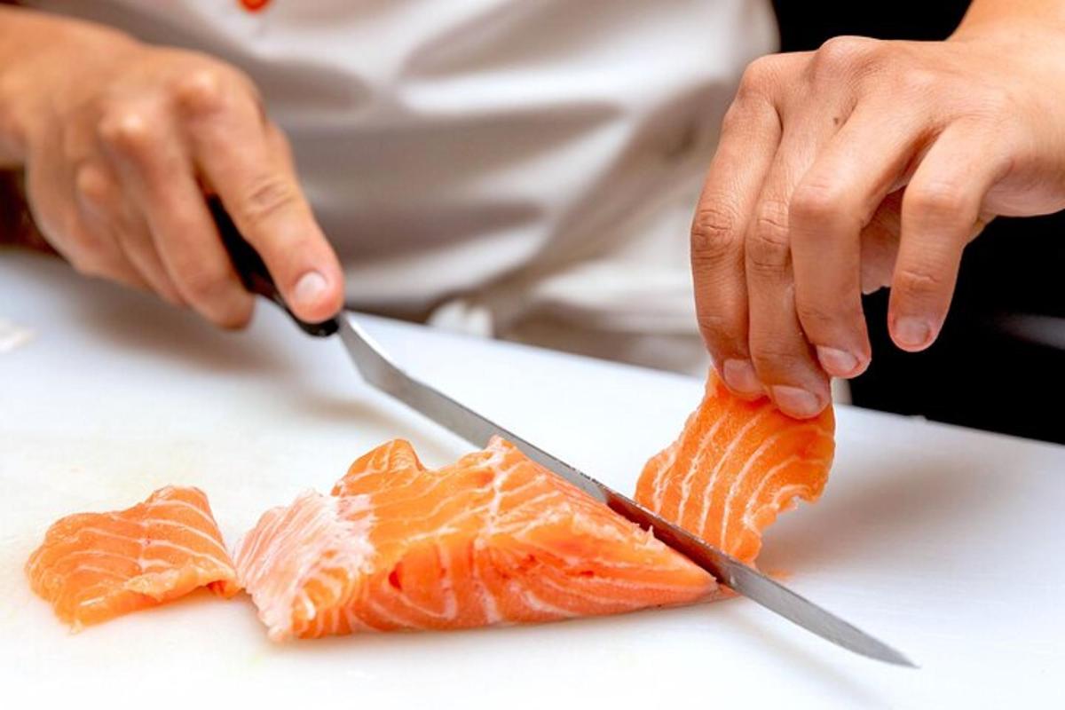 en person som skär en bit sushi med en kniv