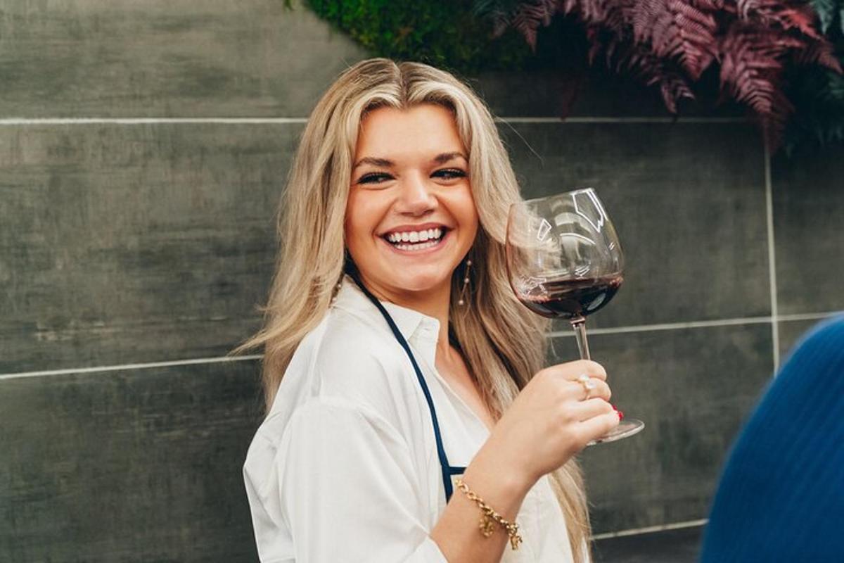 una donna che tiene in mano un bicchiere di vino rosso