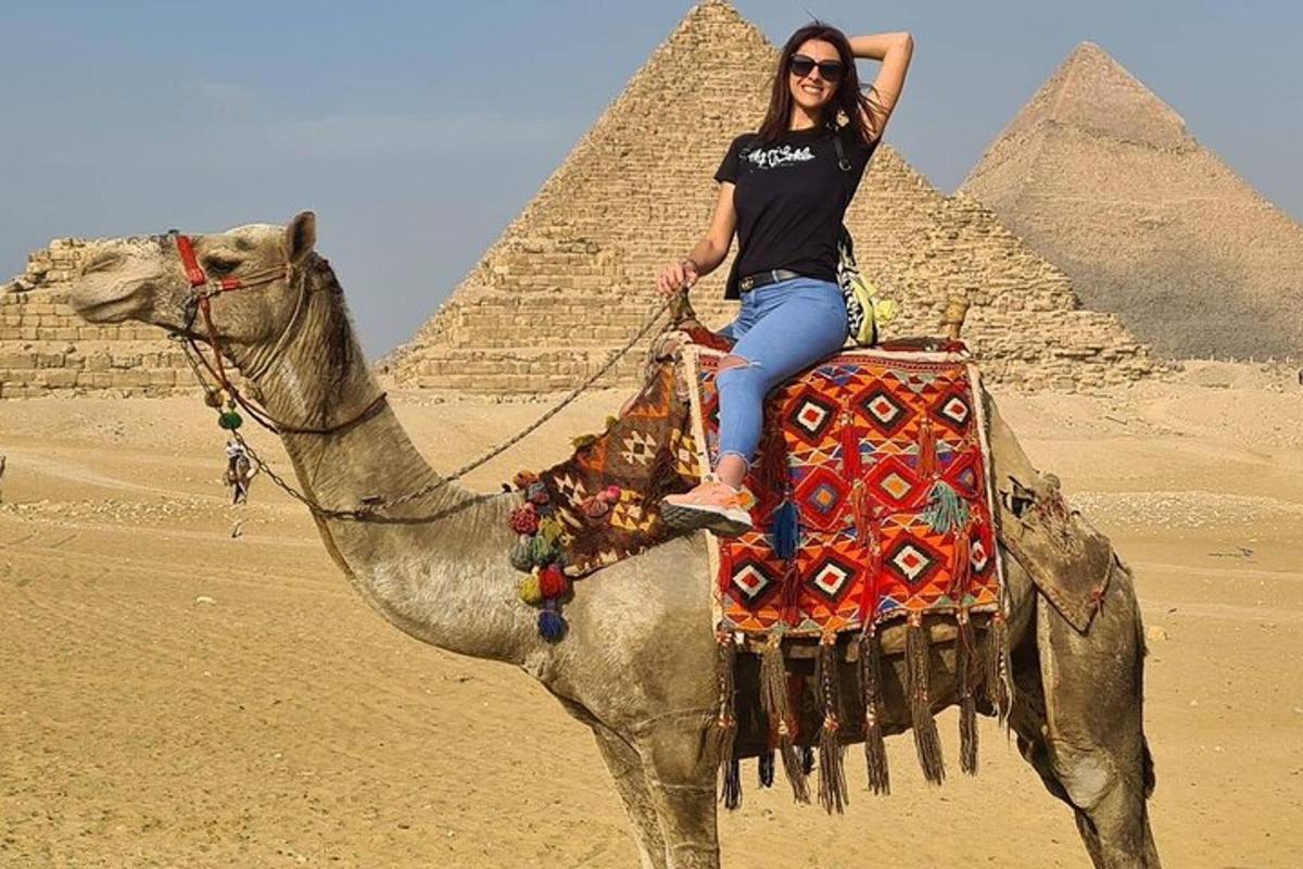 žena jedoucí na velbloudovi před pyramidami