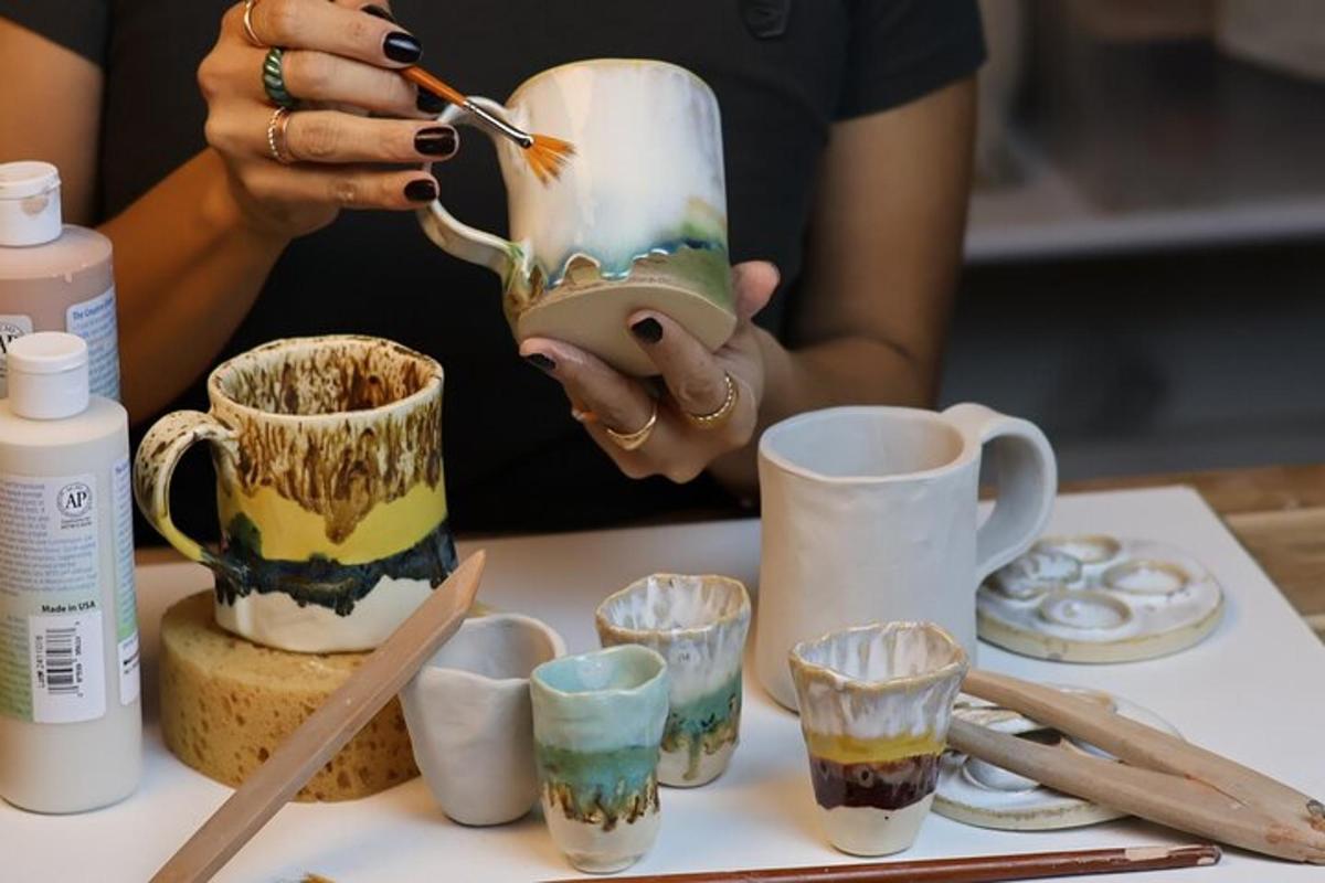 uma mulher está pintando uma xícara sobre uma mesa